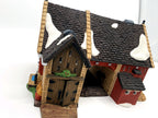 Department 56 Dickens' Village Butter Tub Barn #58338 – front three-quarter view: stone tower with wooden double doors and holly swag, covered archway, red brick, snow-dusted shingle roofs