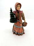 Duncan Royale Babouska of Russia figurine, front view carrying an evergreen tree and a woven gift basket (enhanced)