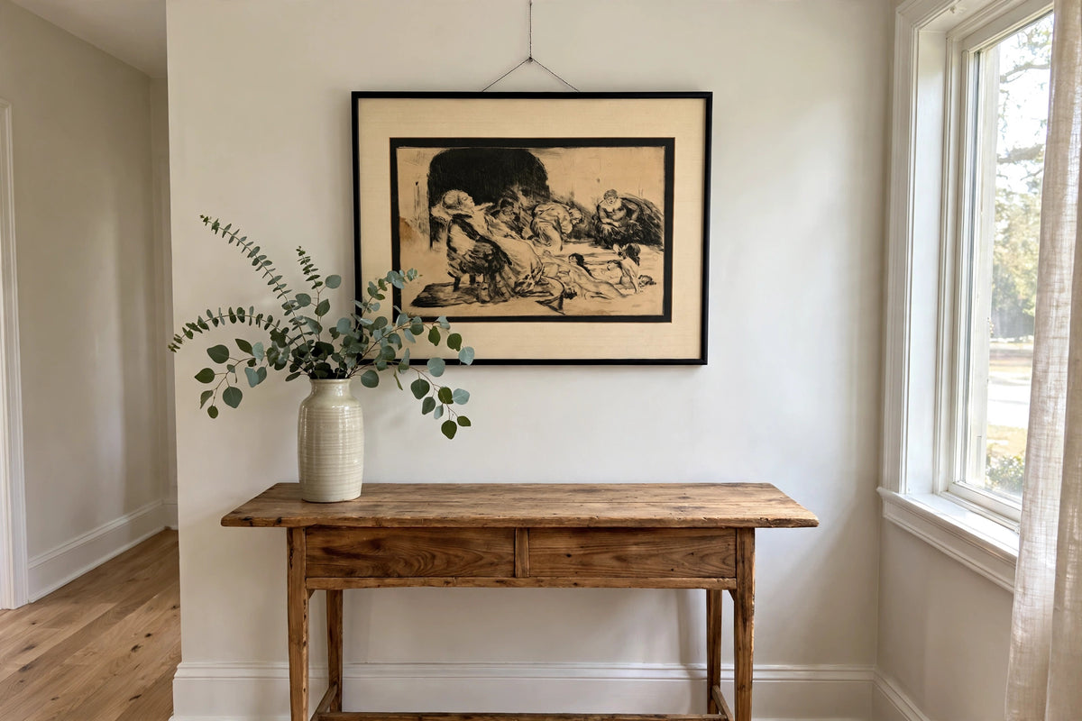 Styled lifestyle photo — the framed Bathers etching above a wooden console table in a bright entryway (display inspiration)
