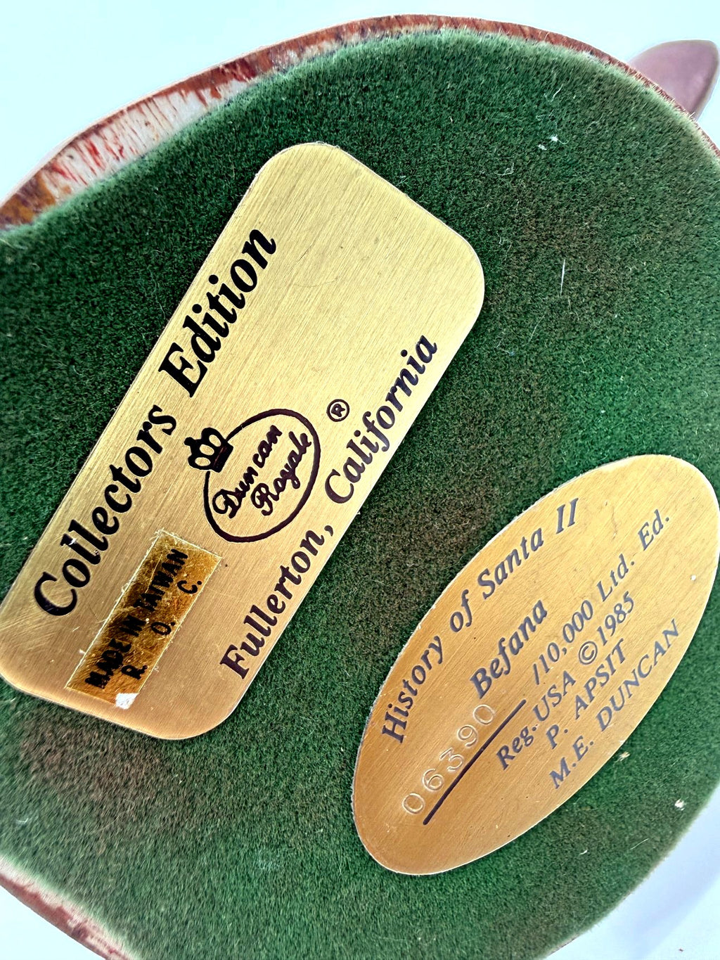 Underside: both gold identification plates on green felt base (enhanced)