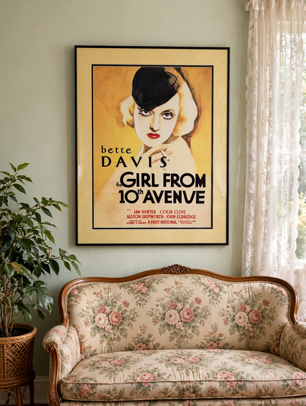 Styled lifestyle photo — the Bette Davis "The Girl from 10th Avenue" framed poster shown in a sunlit vintage parlor above a floral settee (display inspiration)