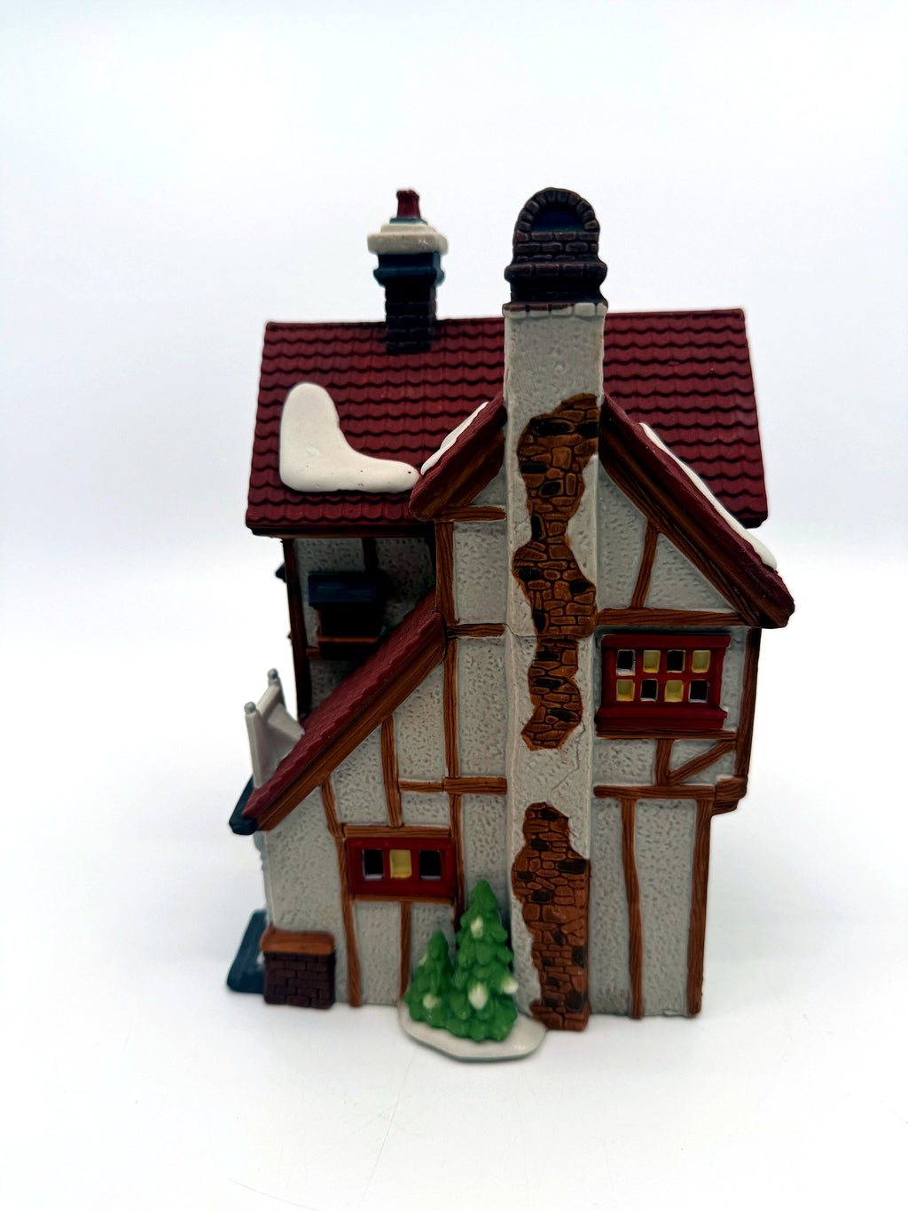 Side view with the stone chimney breast and snow-dusted evergreens
