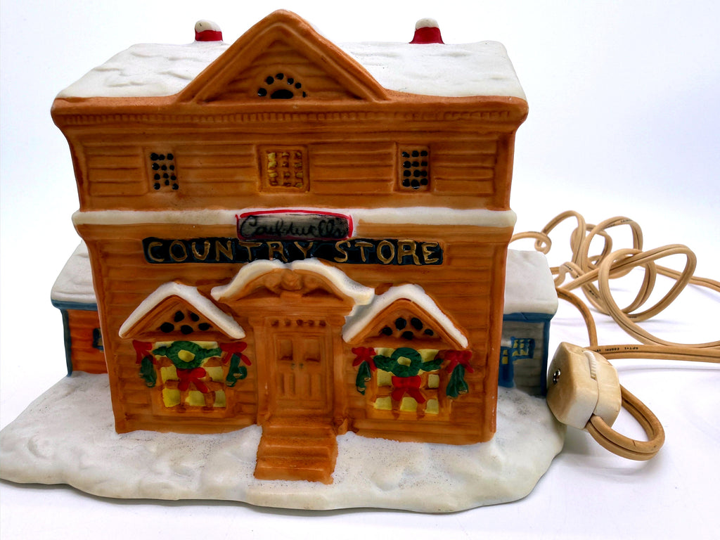 Lighted ceramic Christmas village country store, front view - tan storefront with COUNTRY STORE sign, wreath windows and snow-covered roof