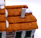 Detail of the textured thatched roof, sculpted snow and white chimney with red cap