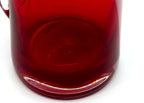 Close-up detail — the thick glass base of the pitcher, with the pontil mark visible through the ruby glass