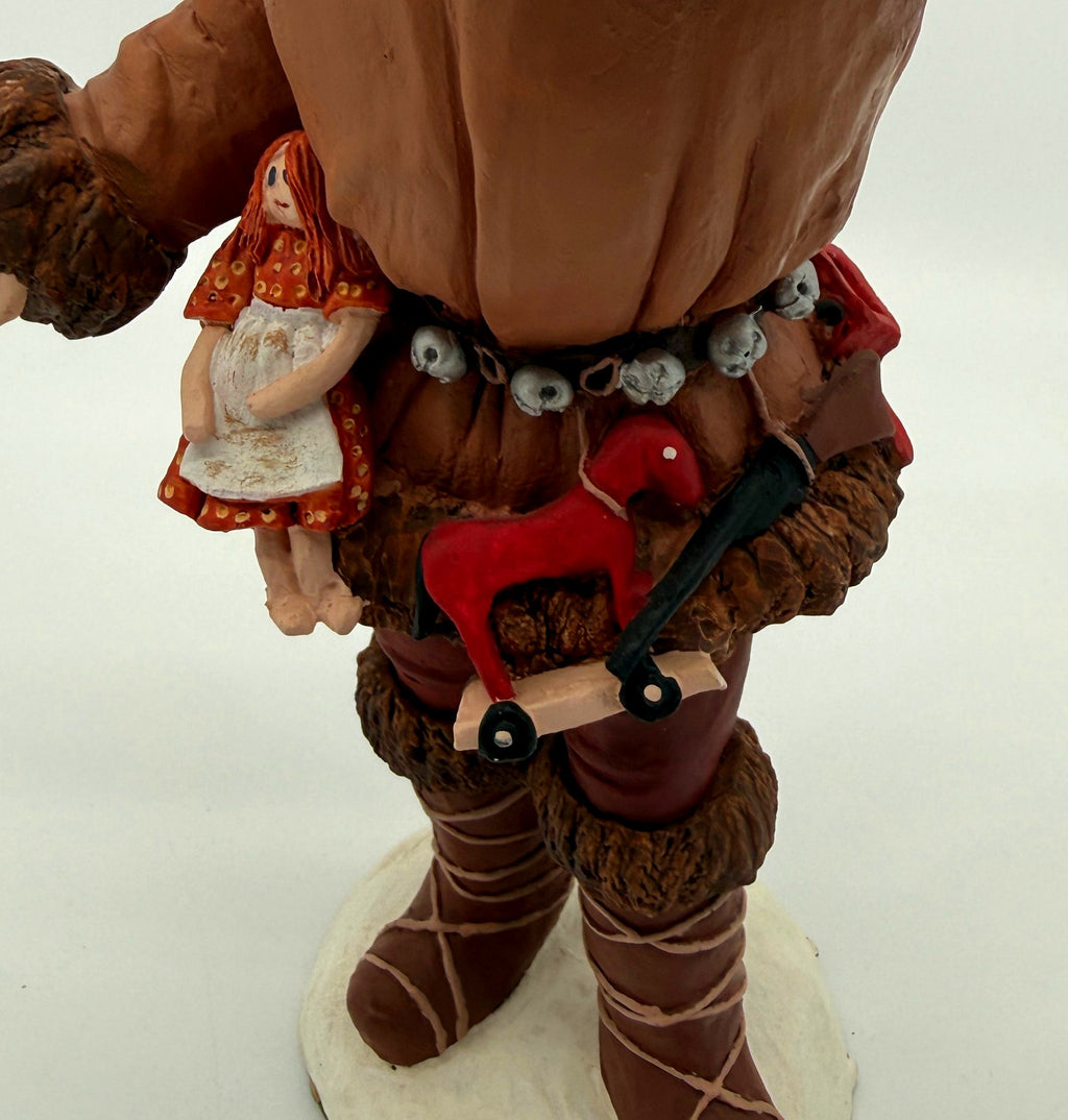 Vintage 1983 Duncan Royale Pioneer Santa figurine – detail of belt toys: doll in a red dress, red rocking horse, toy rifle and lace-up boots