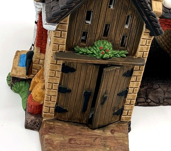 Department 56 Dickens' Village Butter Tub Barn #58338 – detail: wooden double doors with black hinges and holly swag on the stone front