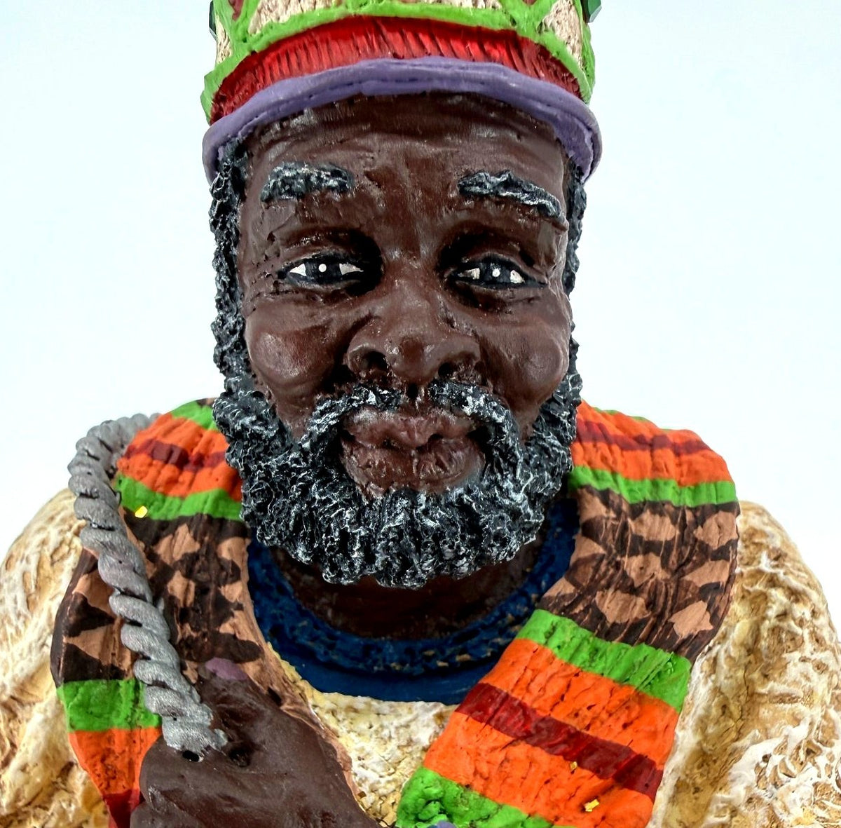 Detail crop — face, gray-flecked beard, jeweled crown and woven-pattern scarf