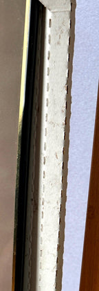 Detail crop — the frame's edge profile: black rail with gold-tone trim, with the original cardboard protector in place