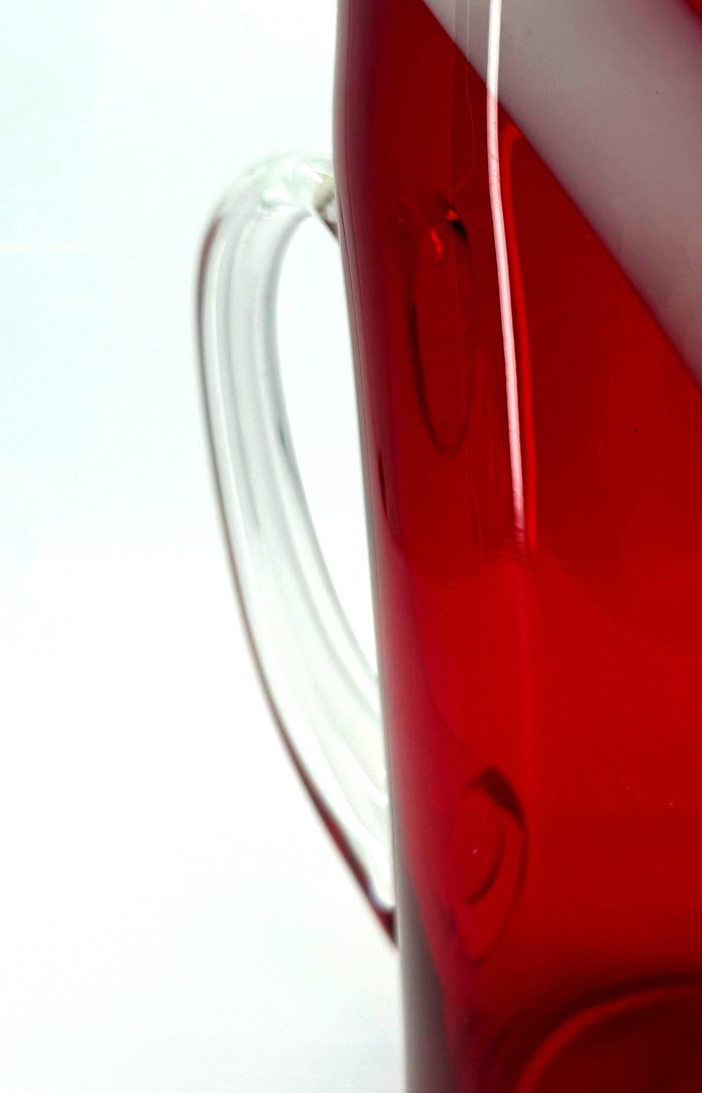 Close-up detail — the clear applied glass handle and its attachment to the body of the pitcher