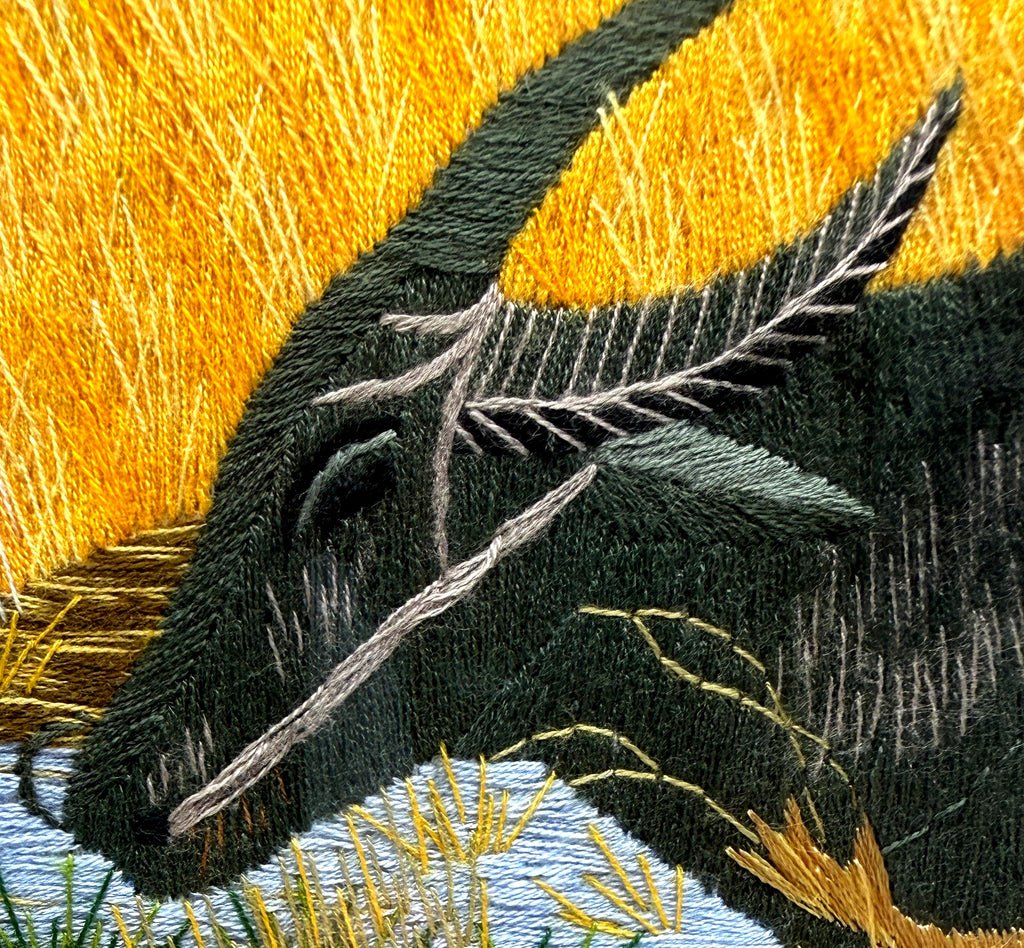 Close-up detail crop — the buffalo's feather-stitched horn, eye and nose rope, showing the layered embroidery threads