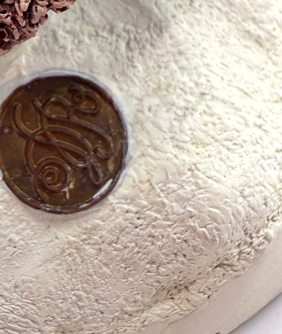 Detail: brass Duncan Royale medallion on the snowy base (detail from seller photo)