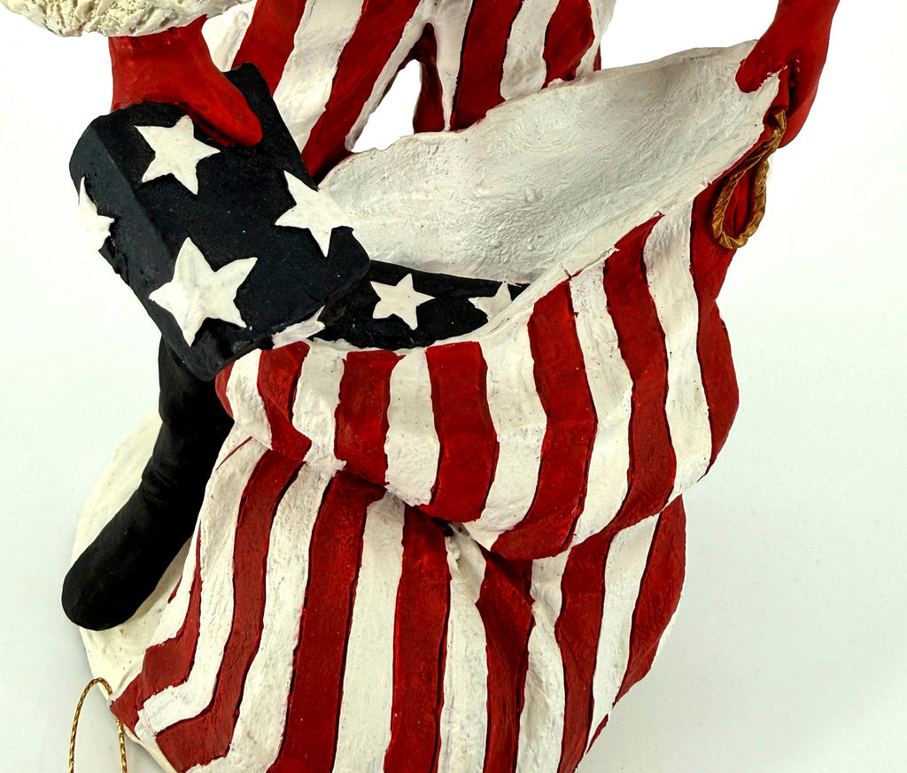 Detail close-up — the star-spangled gift going into the oversized red-and-white striped toy sack, tall black boot beside it