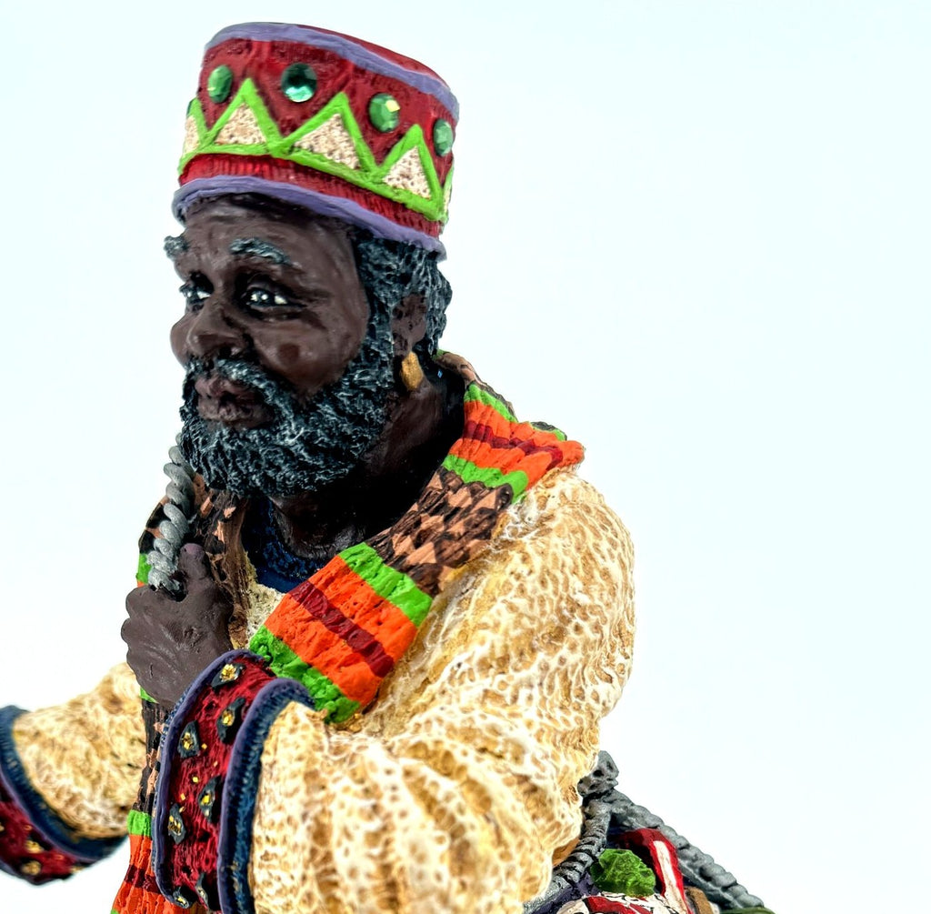 Detail crop — hand-painted face and beard, kente-pattern scarf and gold-flecked red cuff