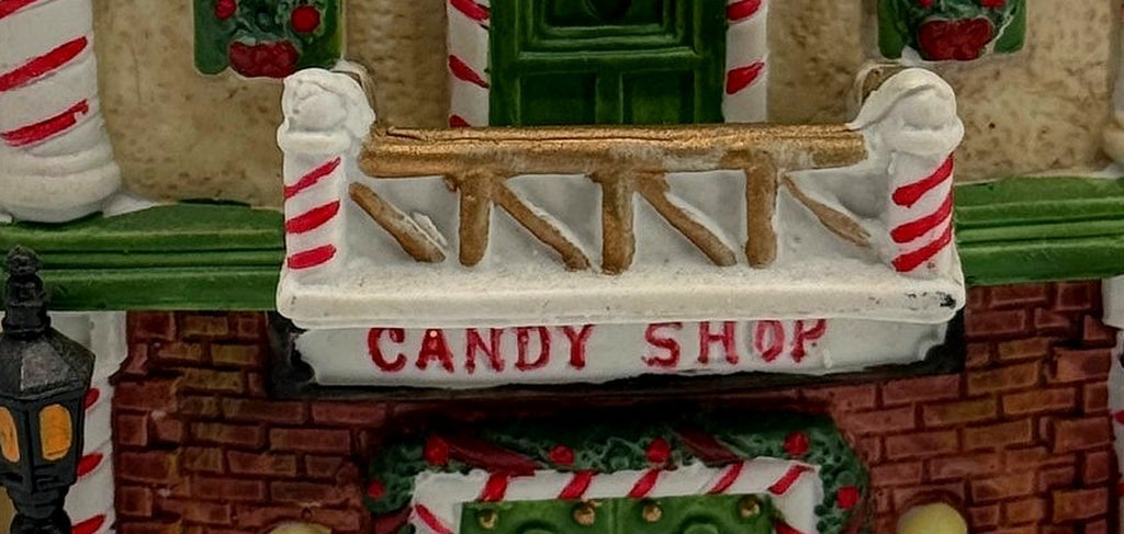 Close-up of the CANDY SHOP sign and snow-dusted balcony with candy-cane posts