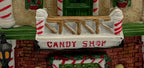 Close-up of the CANDY SHOP sign and snow-dusted balcony with candy-cane posts