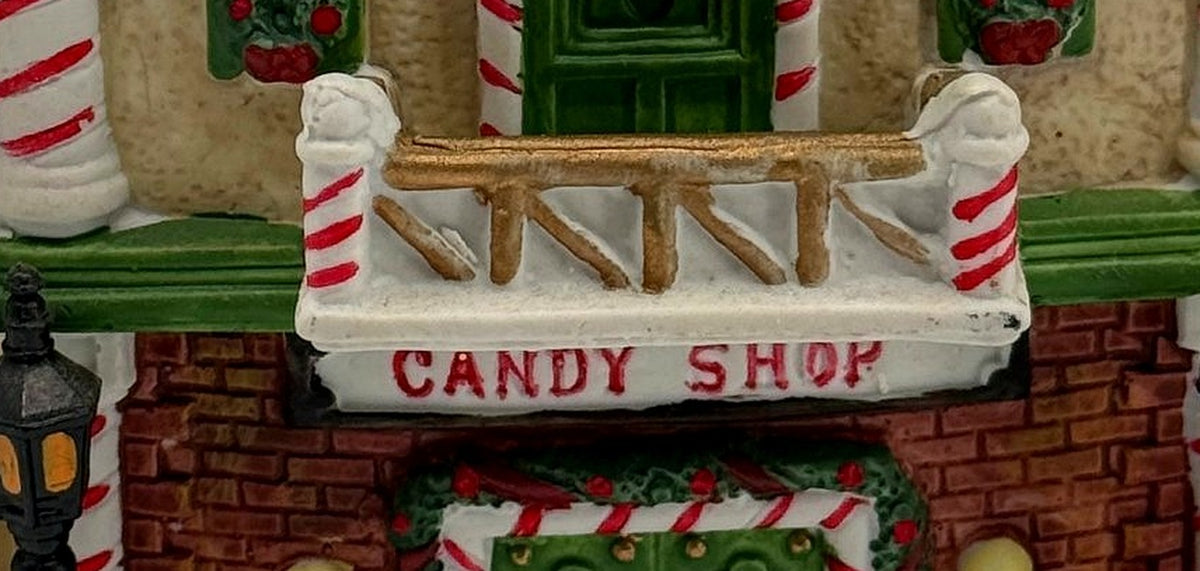 Close-up of the CANDY SHOP sign and snow-dusted balcony with candy-cane posts