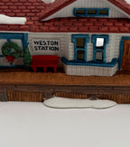Department 56 New England Village Weston Train Station #5931-5 — detail: WESTON STATION sign, wreath, and red bench