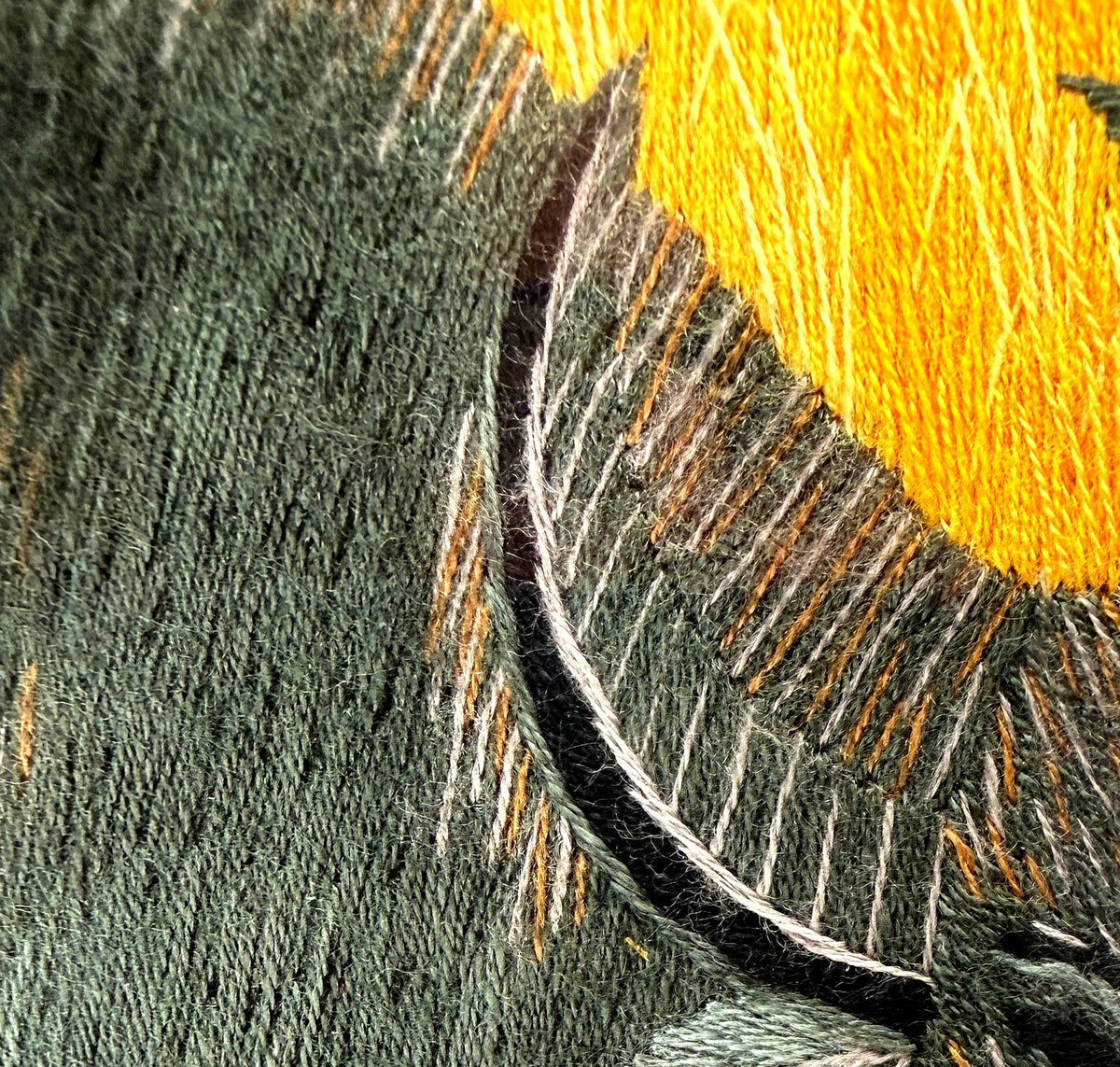 Close-up detail crop — the layered thread work and stitch direction across the buffalo's coat and the golden field