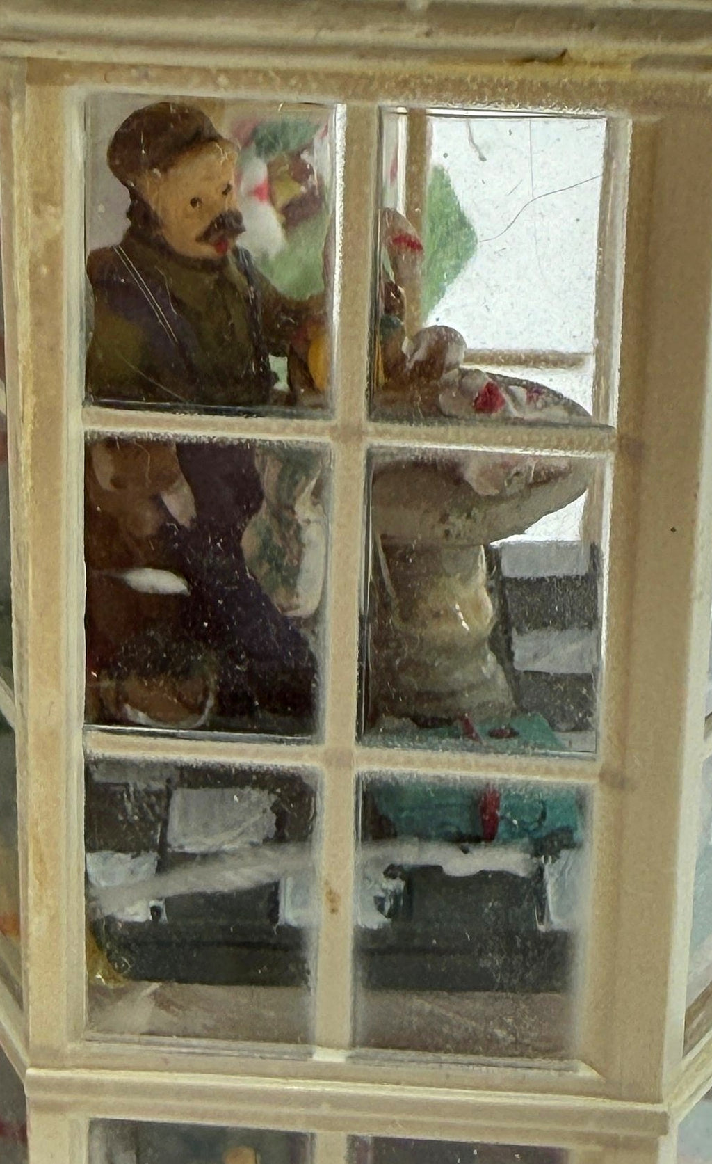 Close-up of the right bay tower interior scenes — a mustached shopkeeper figure behind the counter, seen through the glass panes