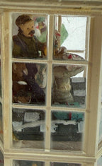Close-up of the right bay tower interior scenes — a mustached shopkeeper figure behind the counter, seen through the glass panes
