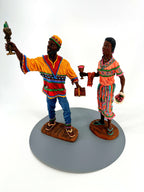 Duncan Collection Kwanzaa figurine pair, 1995, matching No. 0999 — front view: he raises the seven-candle kinara, she holds the unity cup