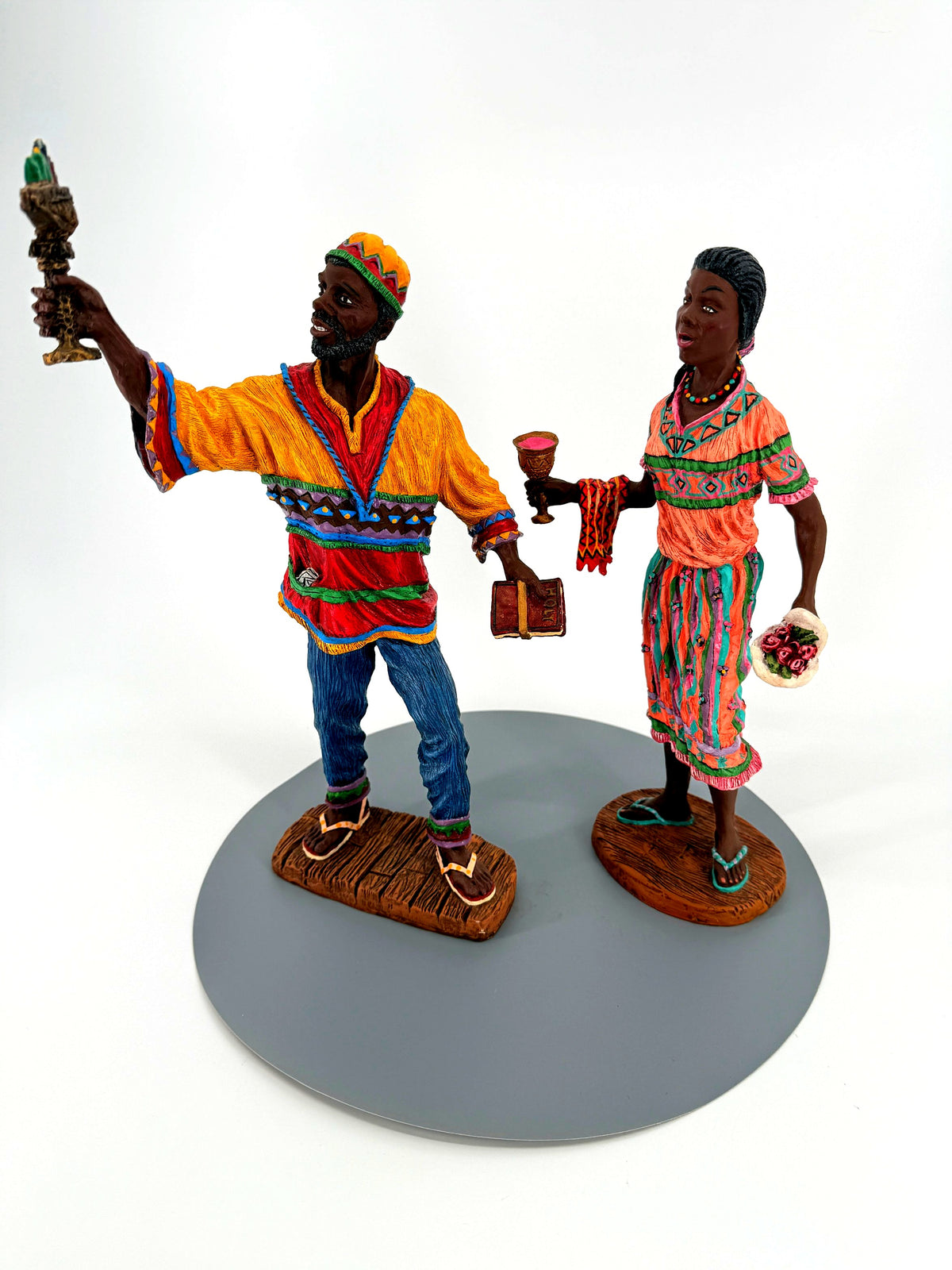 Duncan Collection Kwanzaa figurine pair, 1995, matching No. 0999 — front view: he raises the seven-candle kinara, she holds the unity cup