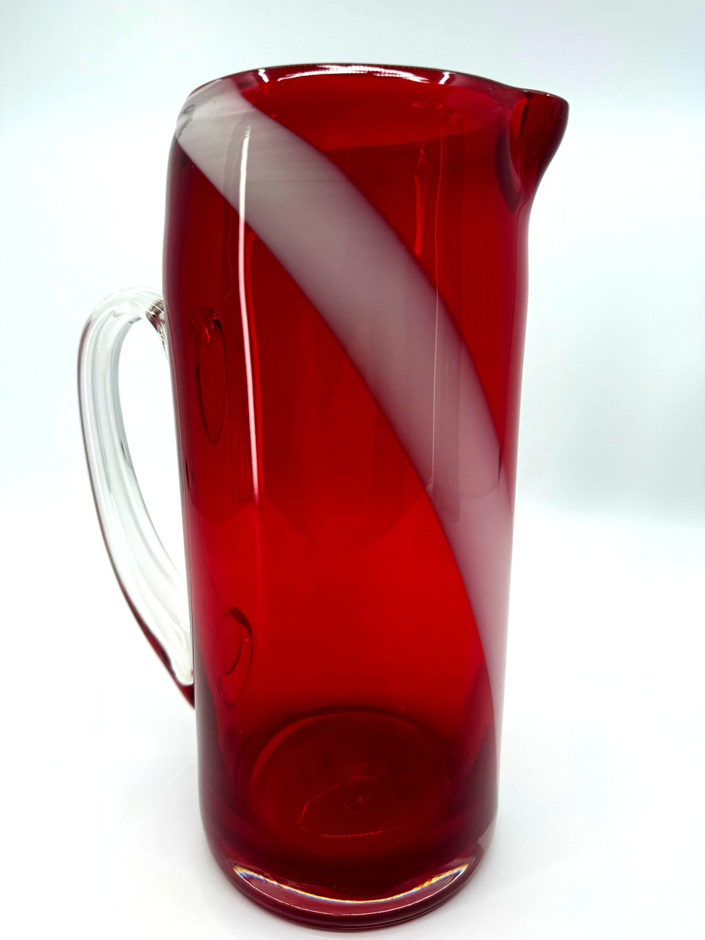 Vintage ruby red glass pitcher with white swirl, 10.5 inch — front three-quarter view showing the diagonal white swirl