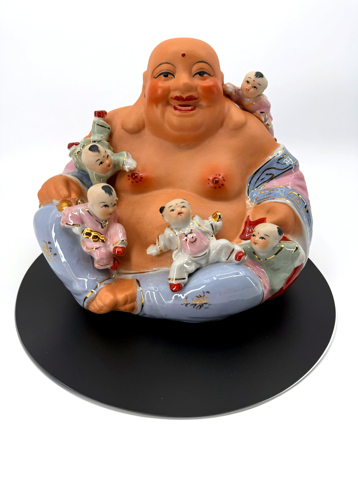 Vintage porcelain smiling Buddha with five children — front view on the round black display base