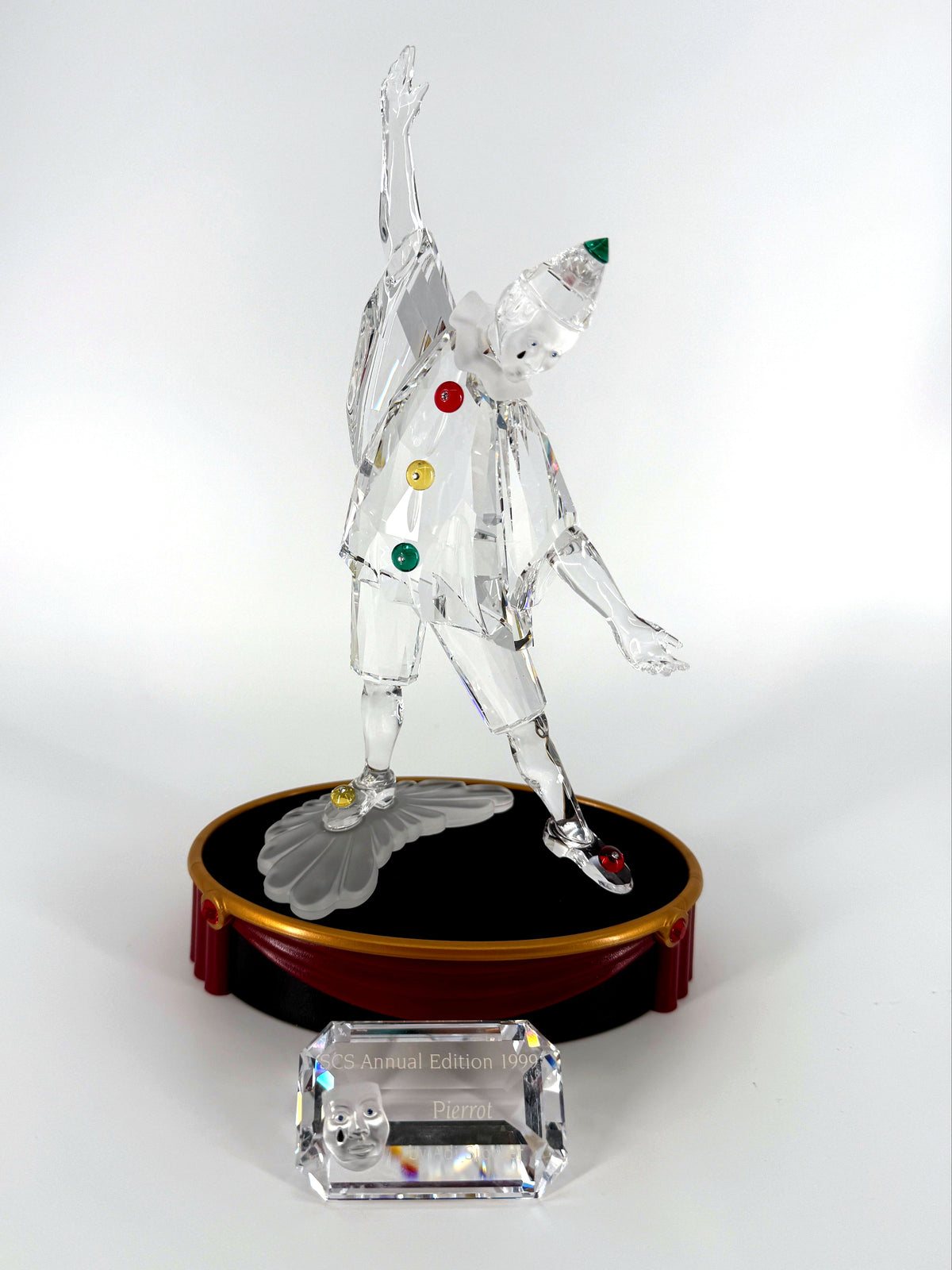 1999 Swarovski SCS Pierrot Masquerade crystal figurine — the figurine on its round display base with the crystal title block in front