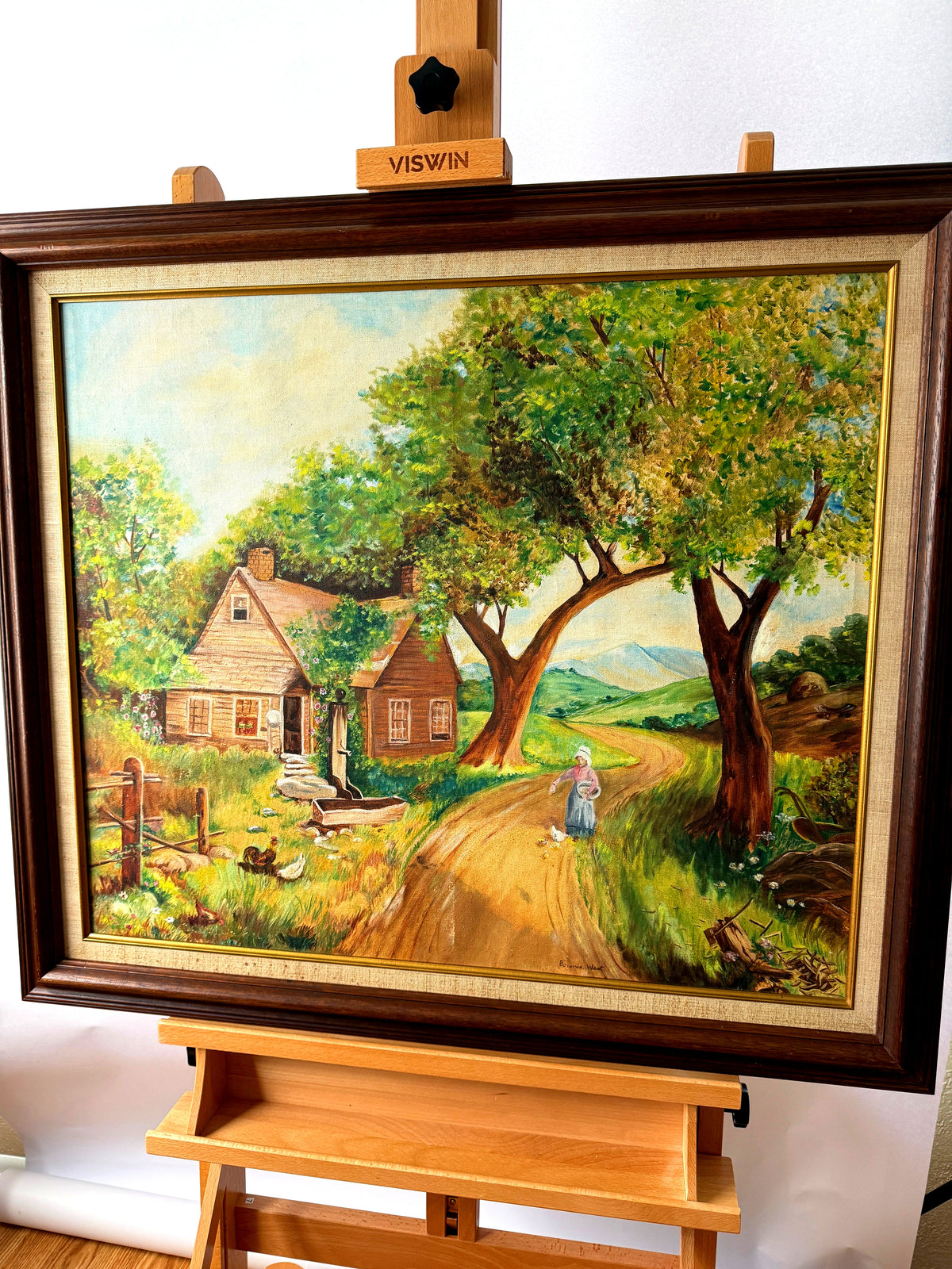 Bonnie West signed country landscape painting, framed — front view on an easel