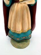 Detail — cream apron with eyelet trim over the teal floral skirt band
