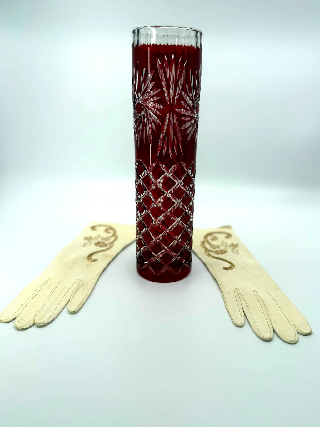 Vintage ruby red cut-to-clear glass vase, 12 inch — the vase flanked by a pair of cream lace gloves, front view