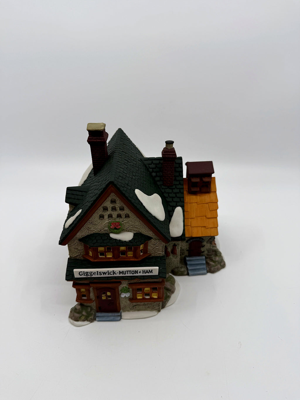 Front angled view showing the stone facade, green shingle roofs and attached golden-roofed side building