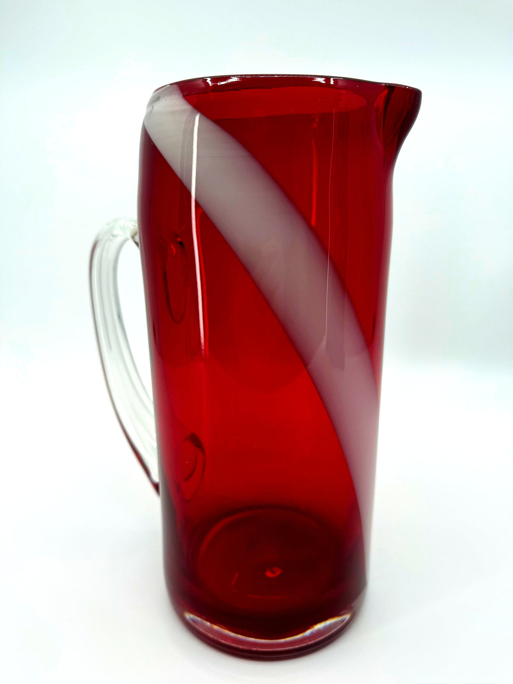 Vintage ruby red glass pitcher with white swirl, 10.5 inch — front view with the clear handle at left