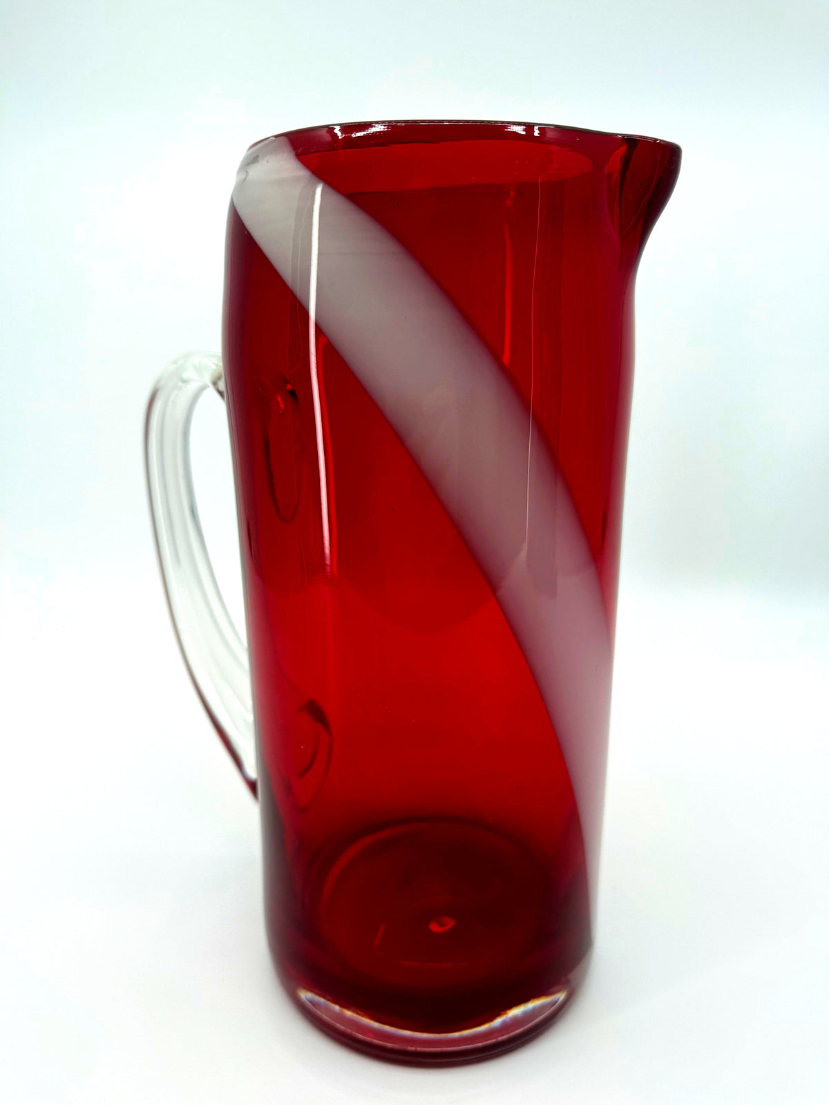 Vintage ruby red glass pitcher with white swirl, 10.5 inch — front view with the clear handle at left