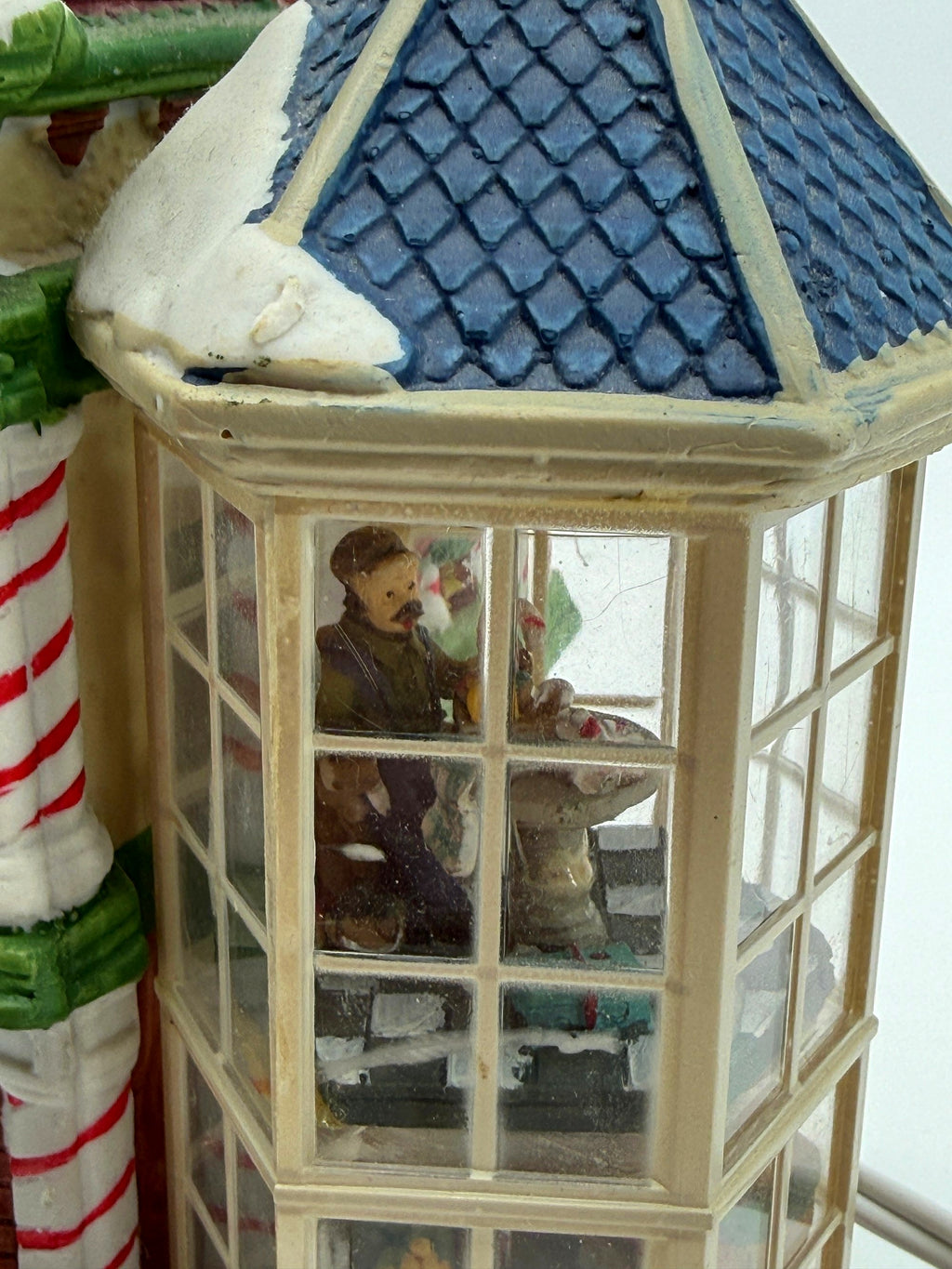 Close-up of the right glass bay tower with its blue shingled roof and the shopkeeper figure inside