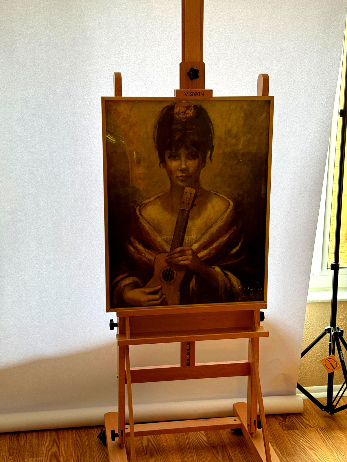 Vintage signed portrait artwork — woman with a guitar, framed — the portrait on an easel, full room view