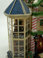 Close-up of the left glass bay tower with its blue shingled roof and two floors of interior figure scenes