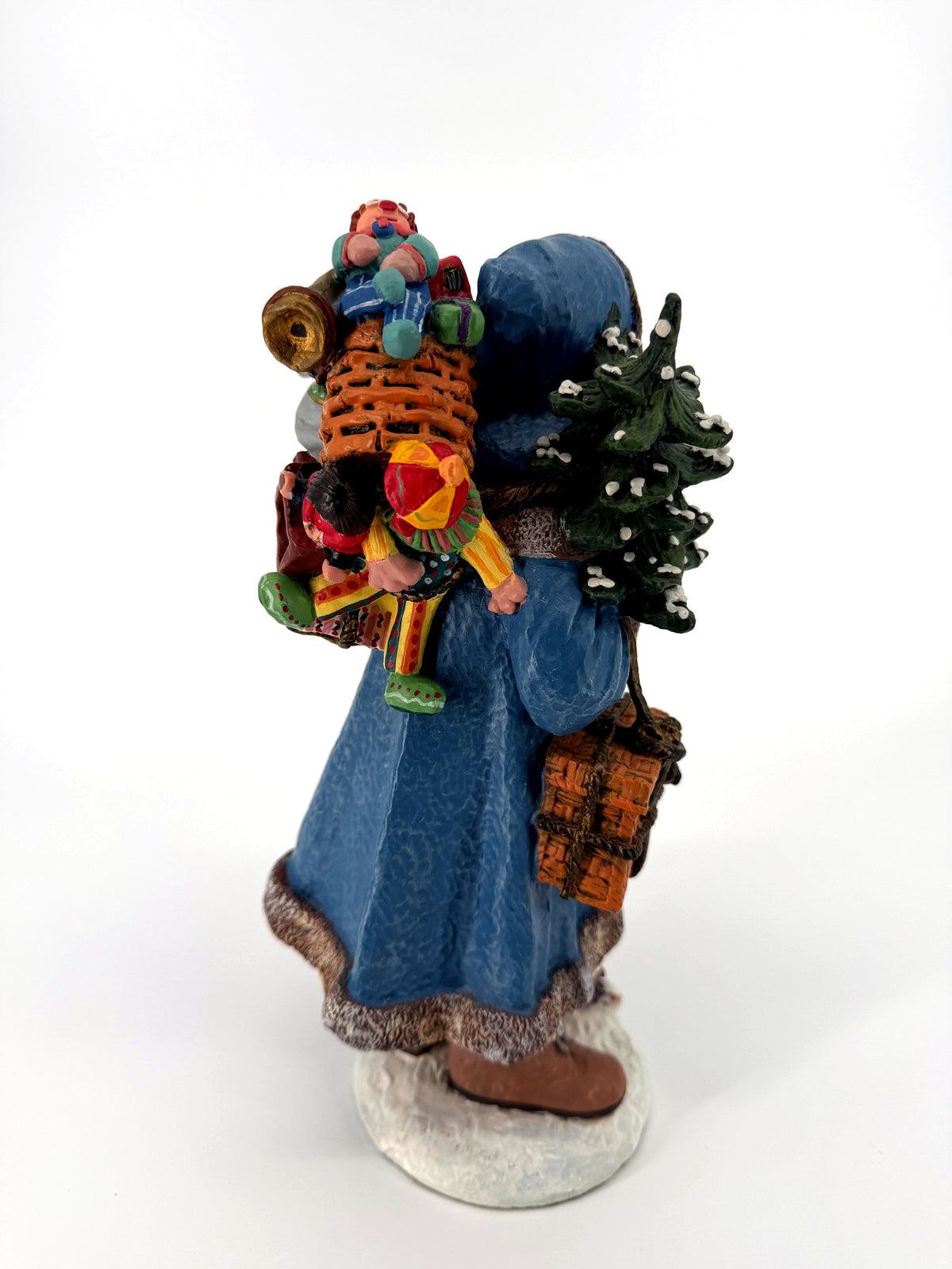 Rear three-quarter view — toy-filled pack basket with dolls, drum and brass horn above the blue coat