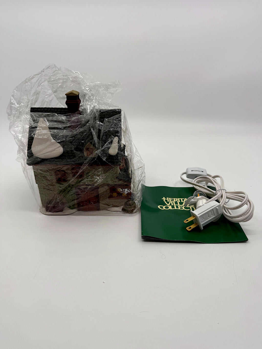 The building in protective wrap, with the new replacement light cord and original Heritage Village booklet