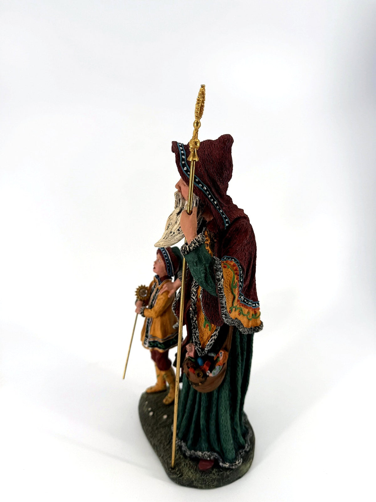 Left side profile — cloak's painted border, toy pouch and the tall gold staff