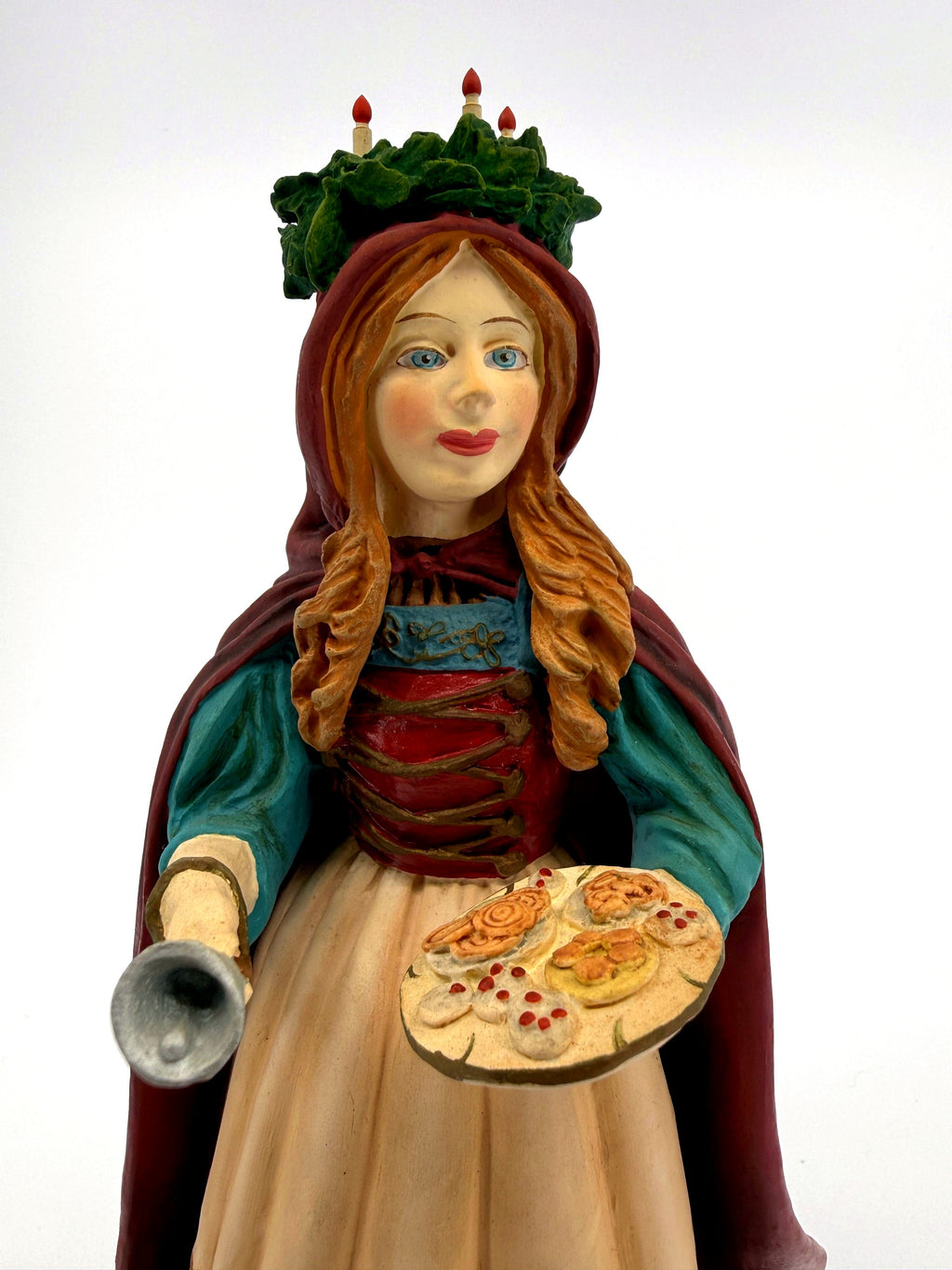 Close-up — hand-painted face, tray of baked goods and silver bell