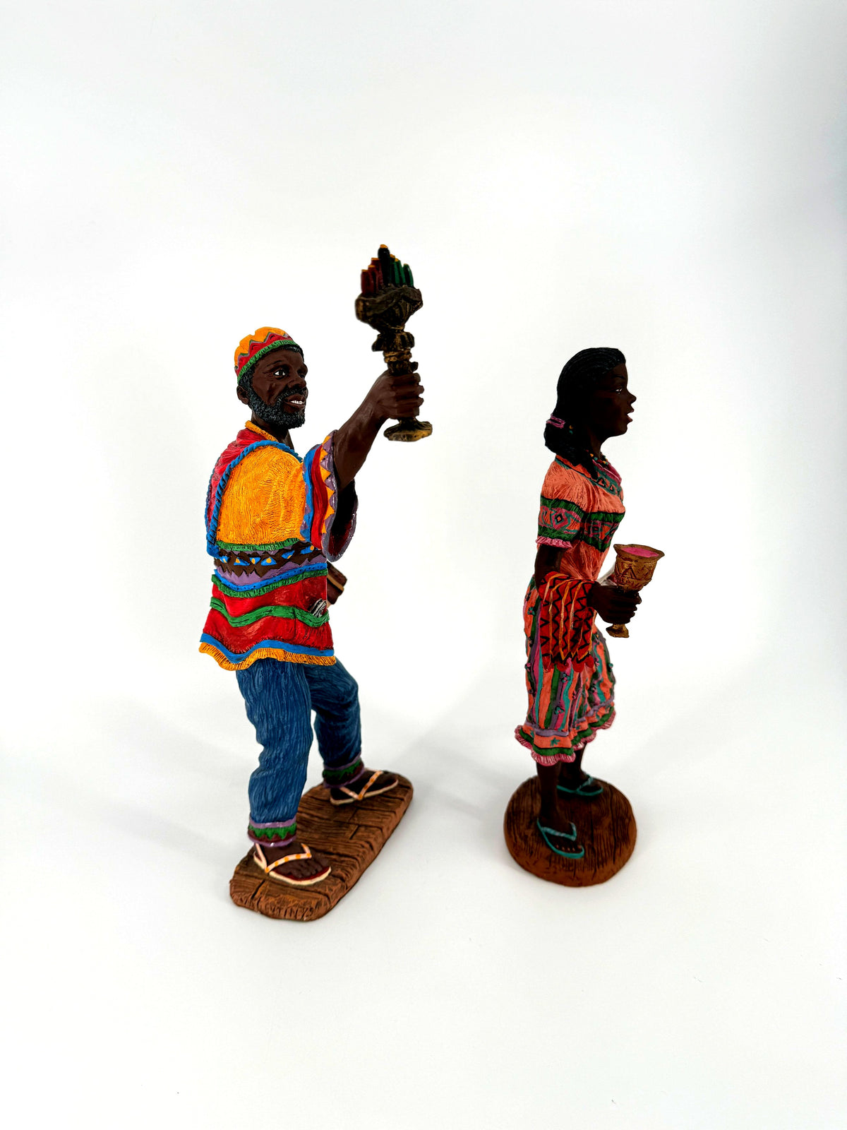 The Kwanzaa pair, three-quarter view from his side — kinara held high