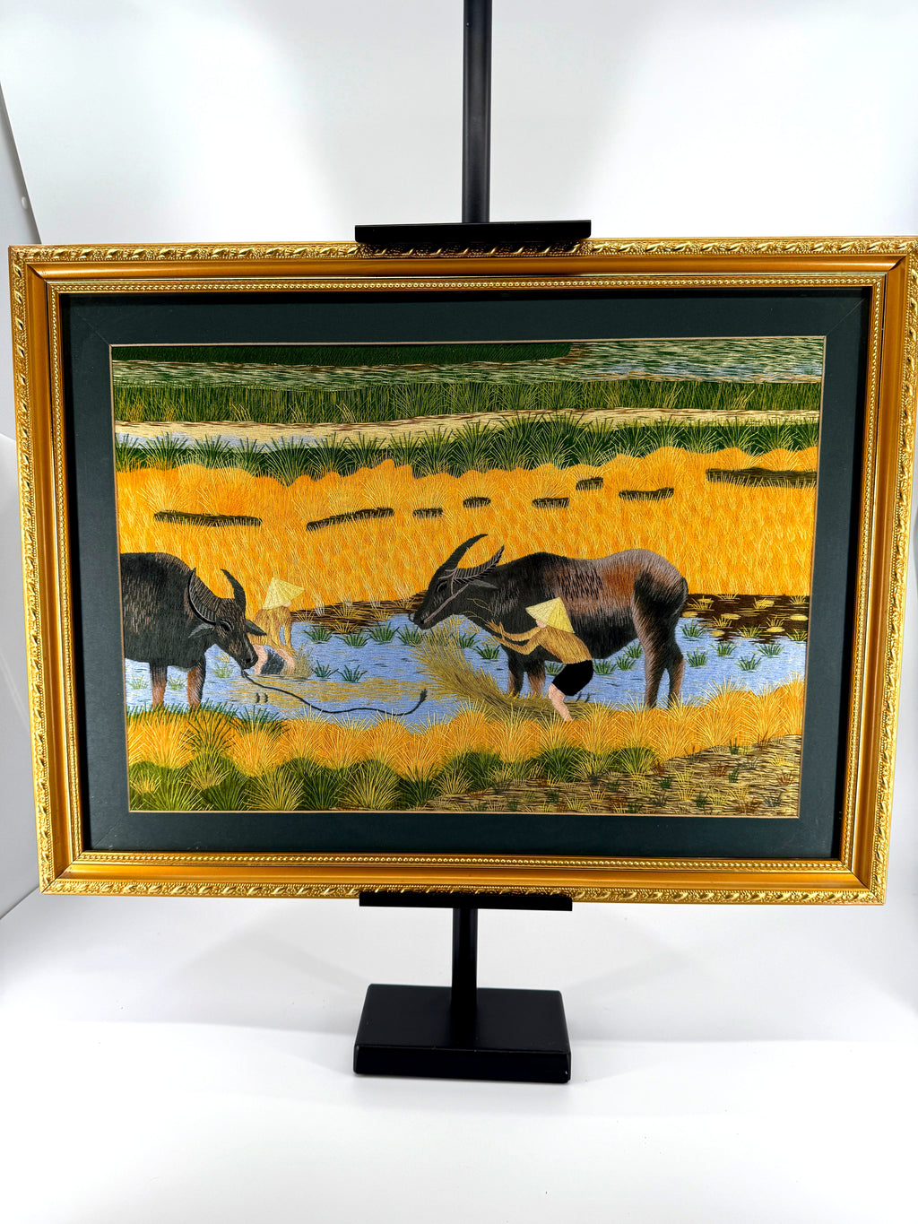 Signed Vietnamese hand-embroidered textile art — water buffalo in rice terraces — the framed piece on its stand, front view