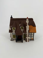 Department 56 Dickens' Village Maylie Cottage #5553-0, Oliver Twist — front view: thatched roof, covered porch, wreath on the red door