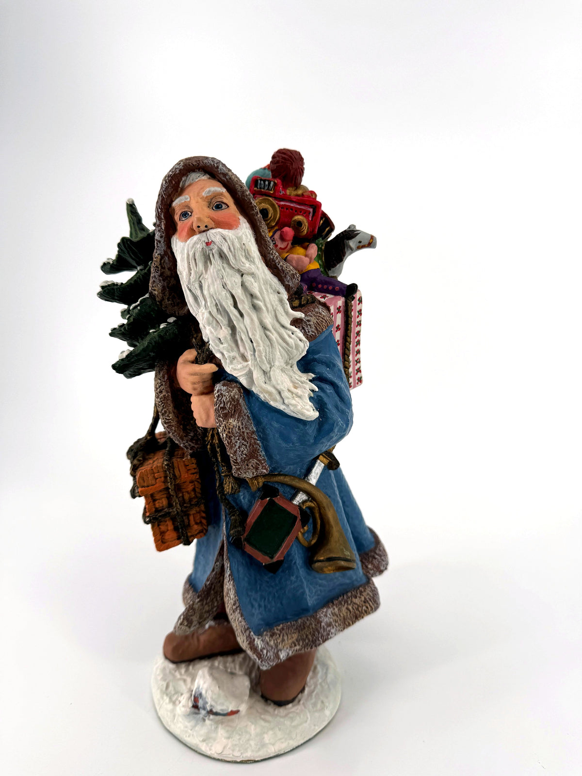 Duncan Royale Winter Santa 1993 figurine, front view — winter-blue fur-trimmed coat, snow-dusted Christmas tree and a pack overflowing with toys
