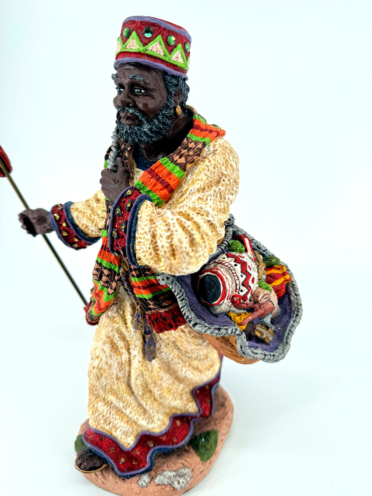 Front view close — hand-painted face, gray-flecked beard, patterned scarf and decorated cuffs