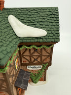 Department 56 Dickens' Village T. Puddlewick Spectacle Shop #58334 — close view of the roof, garland, and T. Puddlewick sign