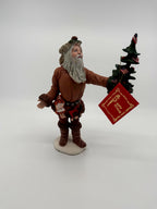 Vintage 1983 Duncan Royale Pioneer Santa figurine – front view with the original red collector's booklet hanging from the tree; brown fur-trimmed pioneer outfit and flag-decorated Christmas tree